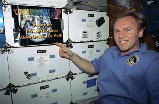 Mission Specialist Andrew Thomas poses with banner "Congratulations Andy, you are the first and last from Down Under on Mir."